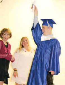 William proudly raises his diploma for all to see.